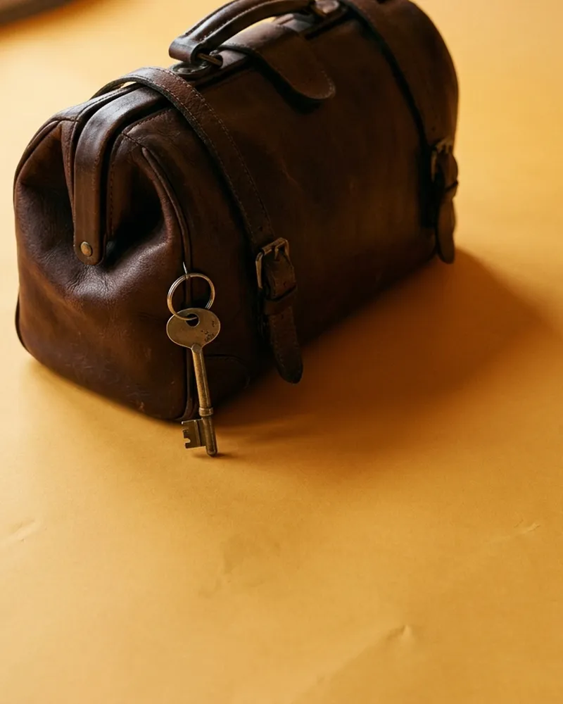 A worn leather doctor's bag with a house key hanging from it.